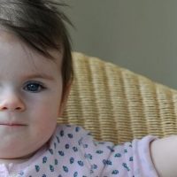 baby girl sitting on couch looking serious and very grown up