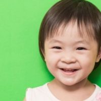 smiling toddler girl on green background