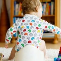 toddler sitting on potty playing with a toy